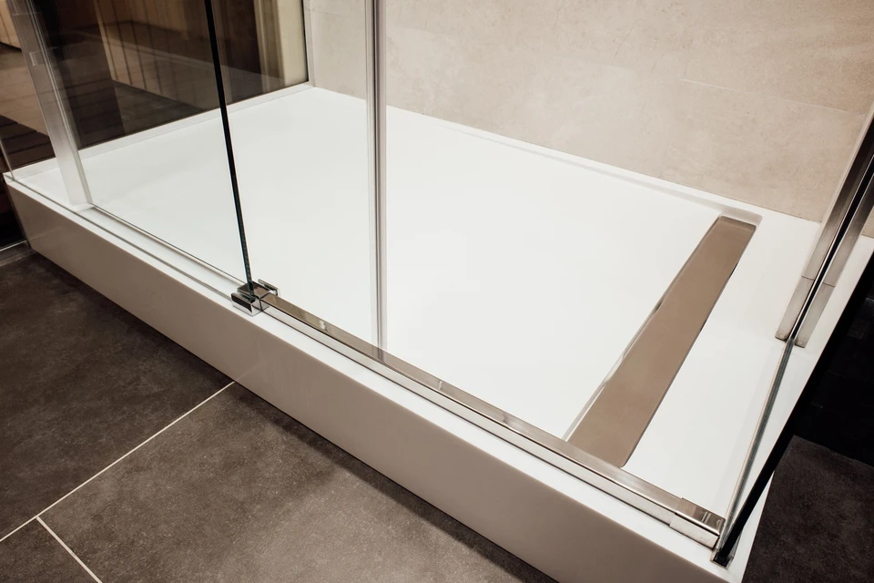 Salle de bain moderne avec baignoire rectangulaire blanche encastrée, paroi de douche en verre trempé avec profilés chromés et charnières pivotantes