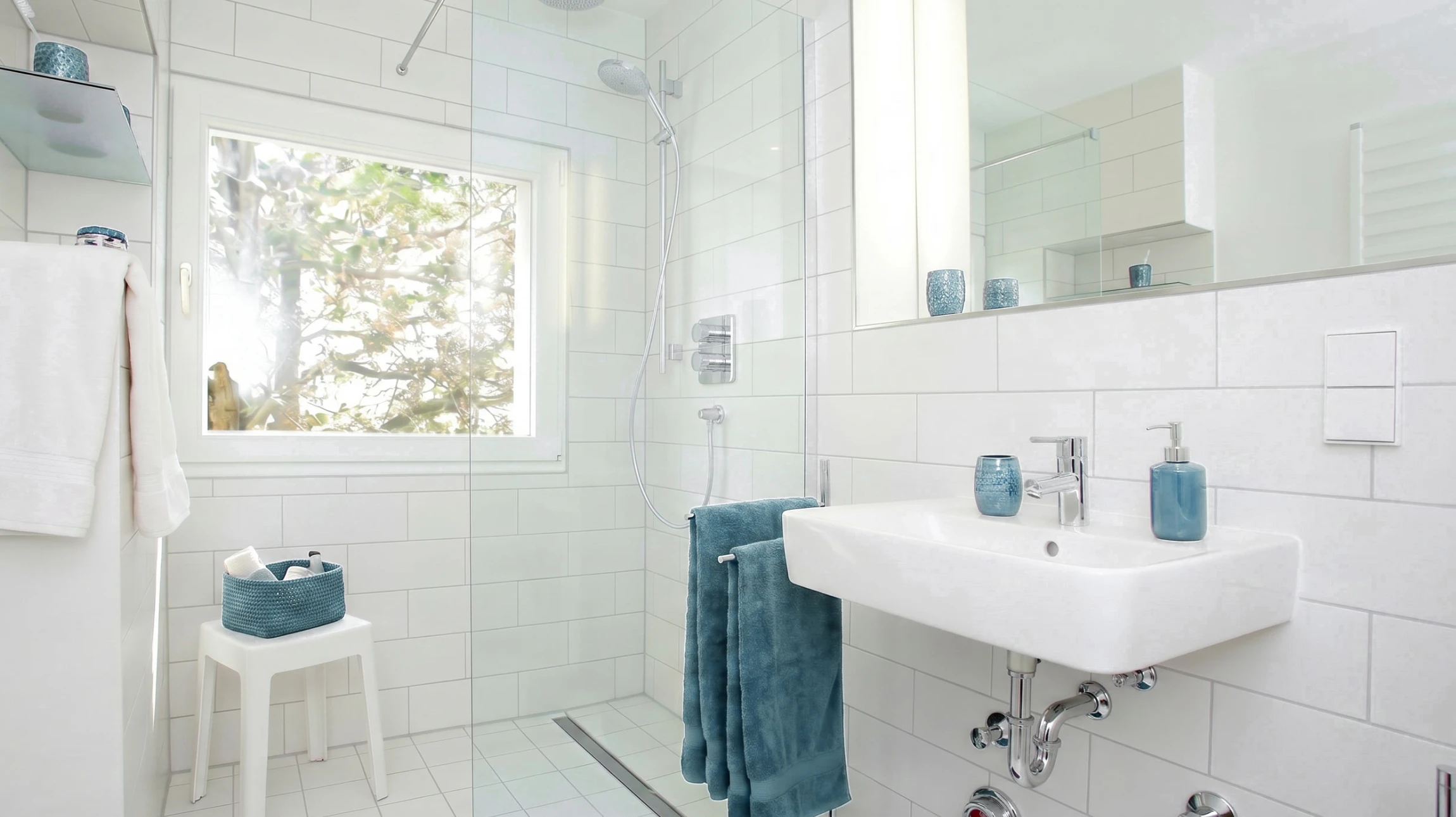 Un homme en combinaison de travail orange installe une barre de sécurité chromée dans une douche carrelée de marbre blanc